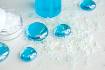 Blue gel spray, drops, glass, bath salt and moisturizer on a white background, top view.