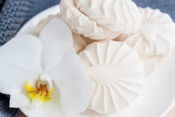 Obraz na płótnie Canvas Marshmallows. Vanilla sweet homemade marshmallows. Light composition with an Orchid flower. Sweet delicious dessert.