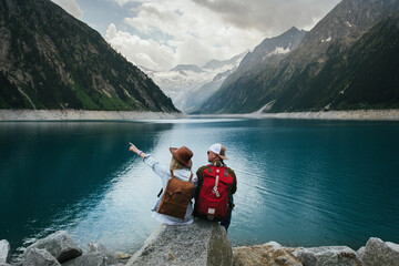 Travelers couple look at the mountain lake. People with a backpack travel. Adventure and travel in the mountains region. Zillertal Alps, Austria.