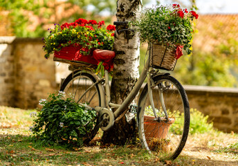 Mit Blumen geschmücktes Fahrrad als dekoratives Element im Garten