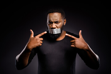 Photo of voiceless speechless afro american guy close cover adhesive tape lips point index finger...