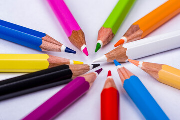 Fototapeta premium Top view on multi colored pencils rotating on white background. Close-up view on bright colored pencils for drawing in motion.