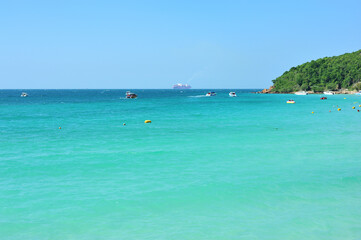 tropical beach with crystal clear turquoise water clear blue sky with boats in the water