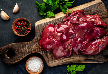 
Raw chicken liver on a cutting board on a stone background. View from above. Space for text