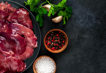 
Raw chicken liver on a black plate on a stone background. View from above. Space for text