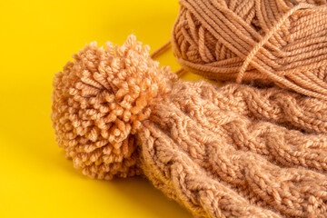 Fototapeta na wymiar Handmade knitted winter hat on yellow background
