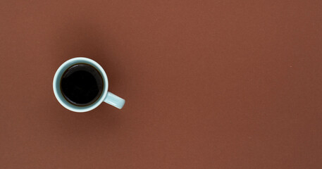Top view, flat lay of black coffee cup on background brown.