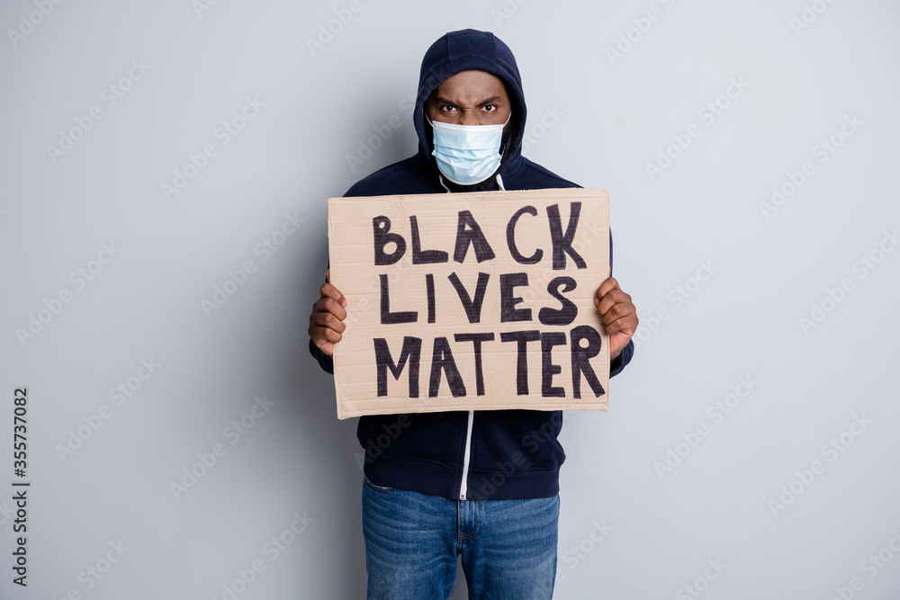 Wall mural Save black lives. Photo of mad dark skin african poor covid infected protester hold placard stand against black citizens lawlessness wear hoodie face mask isolated grey color background