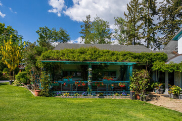 pergola in beautiful summer garden, green conifer trees, green grass and afternoon sun. Luxury...