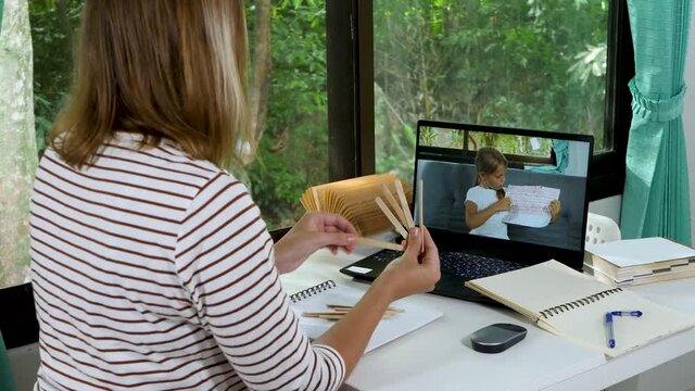 Female teacher has distance education lesson with little school girl pupil. Child make video call to teach math and counting in elementary school online. Online class or e-learning at home