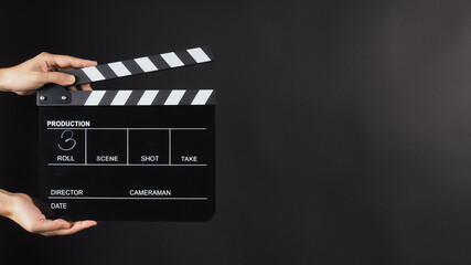 Fototapeta na wymiar A hand is holding black clapper board or movie slate use in video production, movie, film, cinema industry on black background. It has written in number.