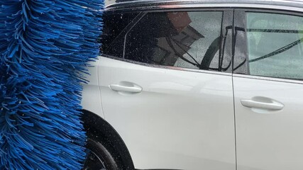 close up view of car washing machine with blue knees cleaning a white car car