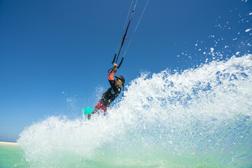 Naklejka premium kiter does a difficult trick on a background of transparent water and blue sky