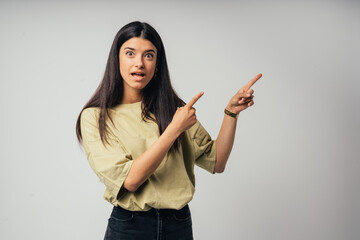 Young handsome caucasian girl  indicates something with his hands. Isolated on gray background
