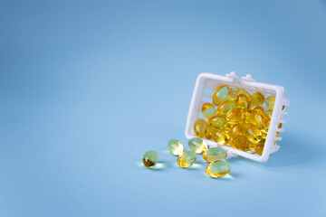 Capsules of omega 3 vitamin supplement isolated on blue background with copy space. Fish oil,...