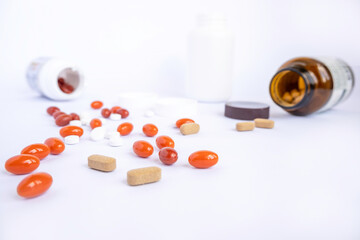 Colored vitamins on white background. Three plastic jars of vitamins with caps and dark glass and vitamins, dietary supplements, capsules, supplements for sports and immunity, scattered next to them.
