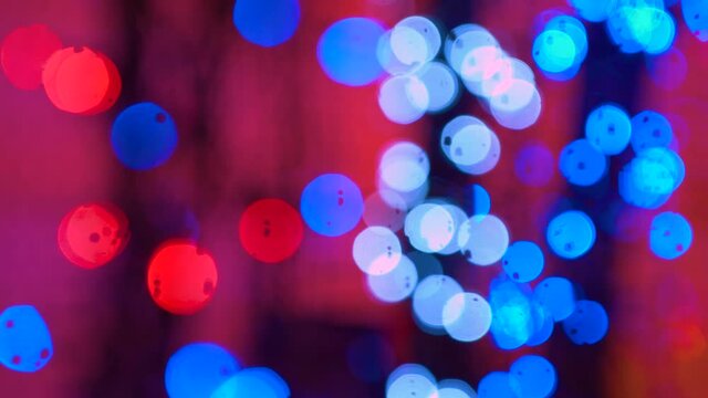 Flashing colored lights in a blur. The bokeh effect. Abstract Disco lights on the backdrop. Club concert dance disco dj matrix beam dmx fashion.Electric Christmas tree lights on red background