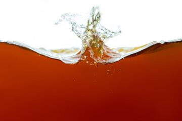 Closeup process of splashing of black tea. Macro shot of liquid in transparent glass. Abstract...