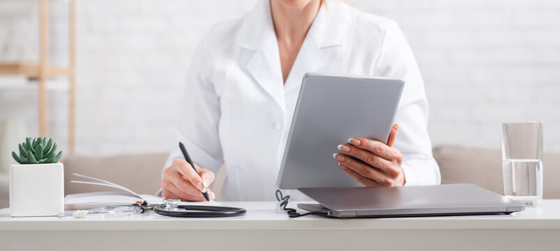 Modern online record to visit to doctor. Woman in uniform with tablet in hands