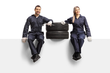 Male and female auto mechanic workers in a uniform sitting on a panel with tires