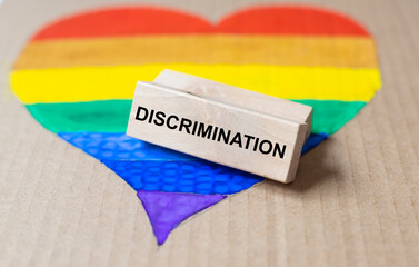 Discrimination word on wooden block on lgbtq flag in heart