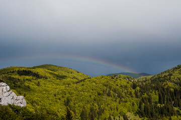 Early summer rainbow above hills. Photographed in the Northern Velebit National Park