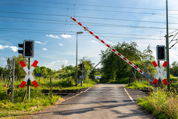 Guarded railroad crossing with closing barriers, red warning light and cross of Saint Andrew.