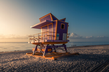 Lifeguard tower in early morning light. Fine sand shore in Miami Beach. Colorful sunrise