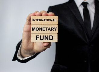 The IMF, the International Monetary Fund, is written on wooden blocks in the hands of a man in a business suit.