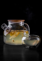 tea pot and Cup of ginger tea with honey and lemon on black background
