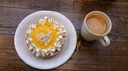 Vanilla cream tart with meringue topping on the side, over wooden table and cup of coffee, natural lighting