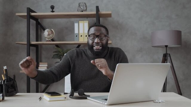 black guy funny dancing with joy at the desktop with a laptop. the joy of success