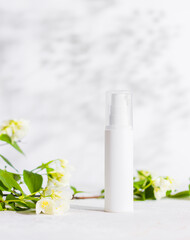 Obraz na płótnie Canvas Unbranded skincare products plastic bottle with dispenser and flacons. Tube for cream shampoo. Green jasmine flowers and their shadows on the white background isolated. Mockup and copy space