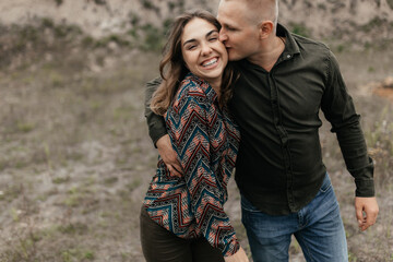 Man kissing his smiling woman while walking in nature. Happy couple