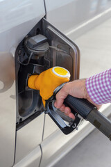 Refueling car at a gas station. Car fuel tank and gas pump. Close-up of man hand filling fuel