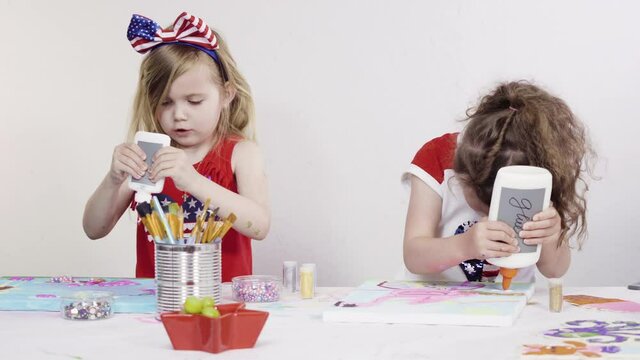 Little girls are painting on canvas on July 4th party.
