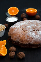 orange and walnut cake on black background.