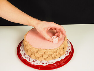 Baker adding a pink rose onto a pink marzipan coverd layer cake