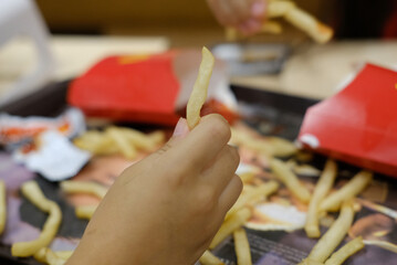 Hand holding fried potatoes in a fast food cafe closeup photo