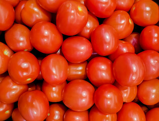 A solid background of ripe tomatoes without leaves. A lot of organic red tomatoes. Useful and affordable vegetables in the supermarket, source of vitamin C. Pattern for design. View from above.