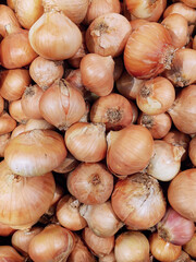 A solid background of unpeeled onions at the market.
