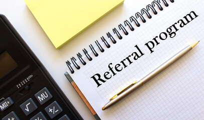 The calculator is next to the notebook. A pen. In the notebook there is an inscription. Office table.