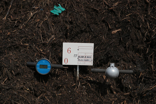 Composting thermometer placed on a windrow. It indicates a temperature of 75 &deg;C which means that the compost is sanitized and free of pathogens and can be used in agriculture and gardening.  