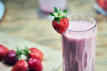 Strawberry shake with strawberries on wooden table. Healthy smoothie and summertime concepts.