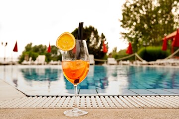 Aperol spritz or coctail on swimming pool side. Concepts of drinks, summer and vacation.