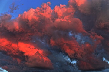 Red blue dramatic storm clouds on sunsen with sun rays reflection in the sky close up on a summer evening, beautiful cloudscape, texture for background and wallpaper