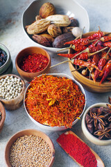 Colorful indian spices and herbs in bowls on light concrete table