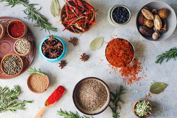 Colorful indian spices and herbs in bowls on light concrete table