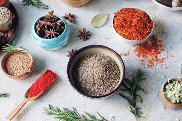 Colorful indian spices and herbs in bowls on light concrete table