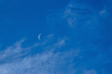 day moon against a blue sky with Cirrus Cumulus clouds